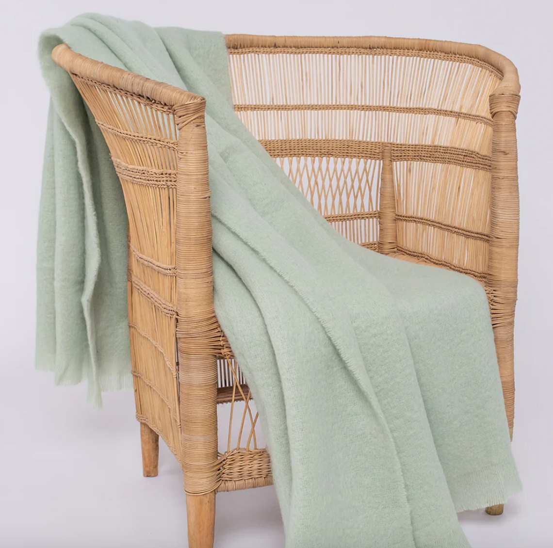 Malawian cane chair with a light pastel green mohair wool blanket on it